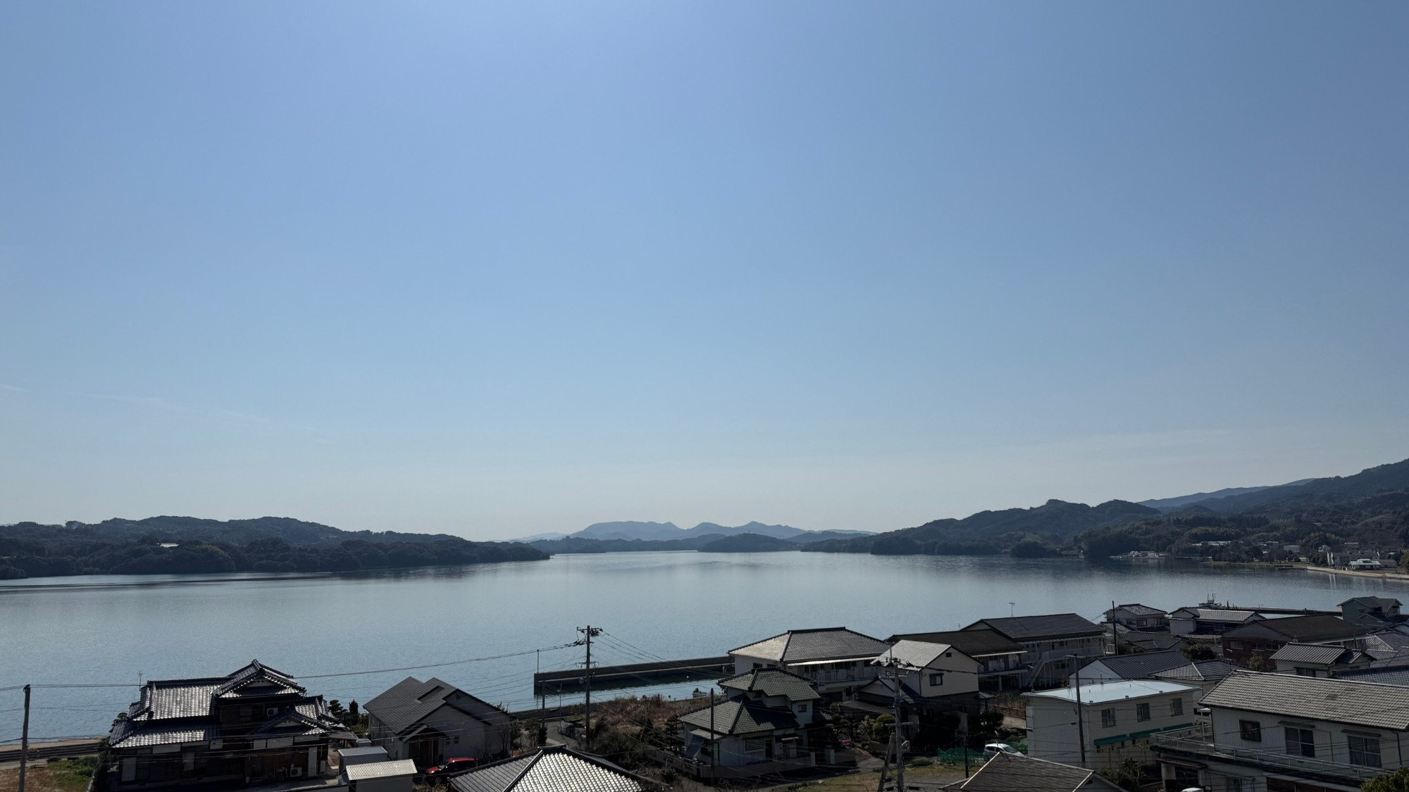 さざなみの丘公園から見おろした形上。手前に家なみ、そのむこうに静かな形上湾と対岸の山がひろがる
